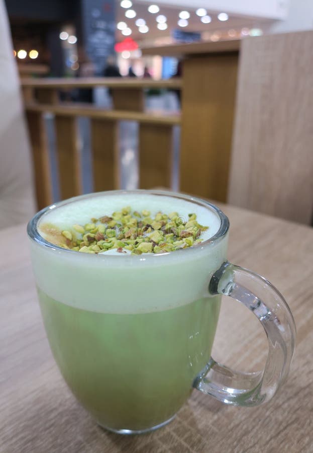 Pistachio Latte Coffee in a Glass Cup with Foam and Nuts Stock Image