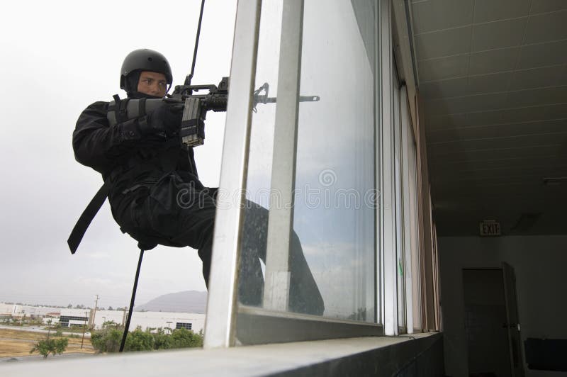 Pistola di Team Officer Rappelling And Aiming dello SCHIAFFO immagini stock libere da diritti Pistola di Team Officer Rappelling And Aiming dello SCHIAFFO immagini stock libere da diritti