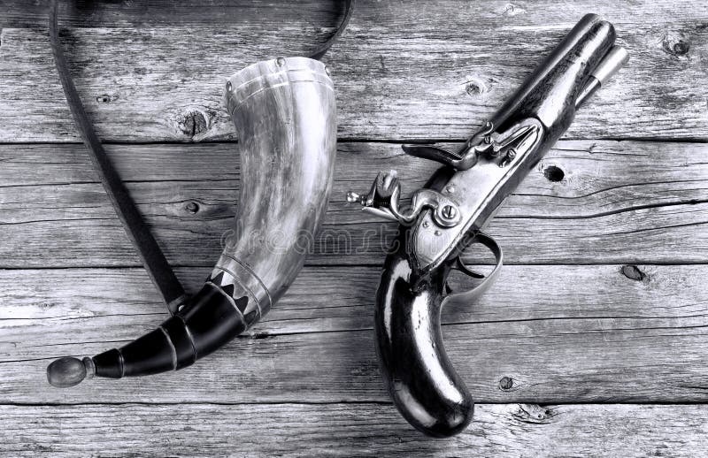 Antique English flintlock pistol and gunpowder horn made around 1800 in black and white. Antique English flintlock pistol and gunpowder horn made around 1800 in black and white