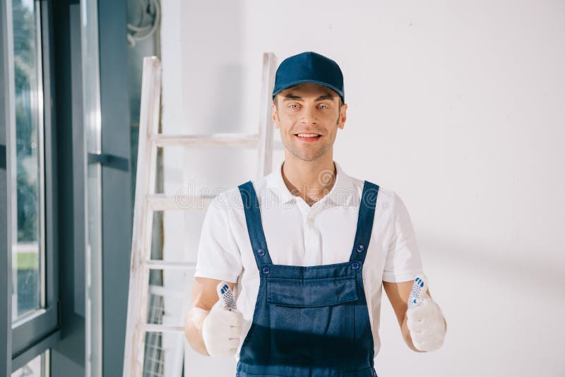 Pittore in uniforme con pollice alzato e sorriso alla telecamera fotografie stock libere da diritti