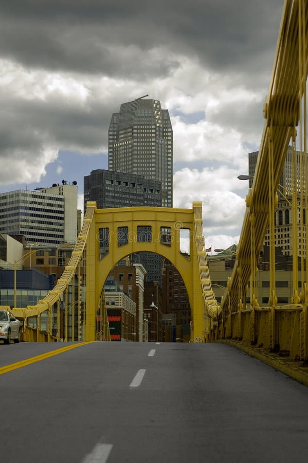 Žluté most v Pittsburghu na zamračený den s modrou oblohu na obzoru.