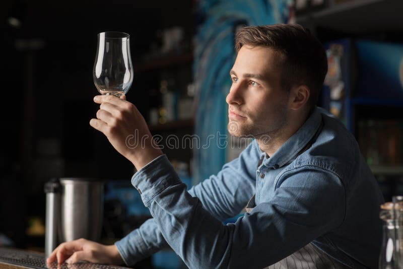 Piwny barman patrzy na czyste szkło stojące za barem fotografia stock