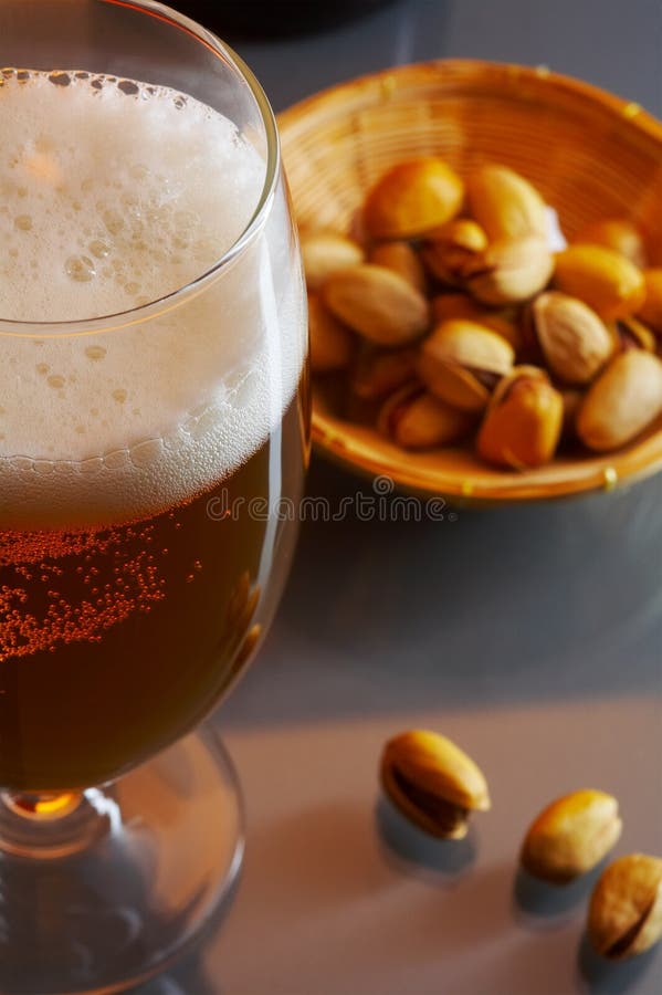 View of nice big glass full of cold fresh beer and some nuts beside. View of nice big glass full of cold fresh beer and some nuts beside