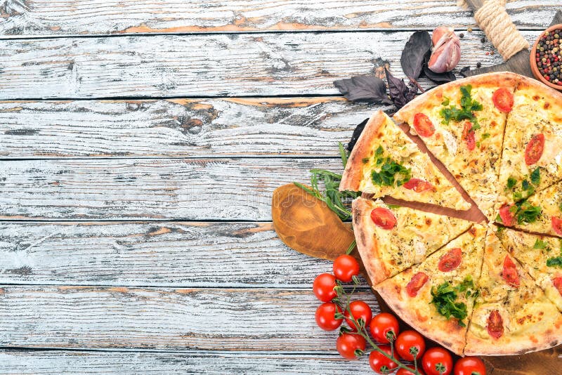 Pizza with cherry tomatoes, suluguni cheese and basil. Italian cuisine. On a wooden background. Free space for text.