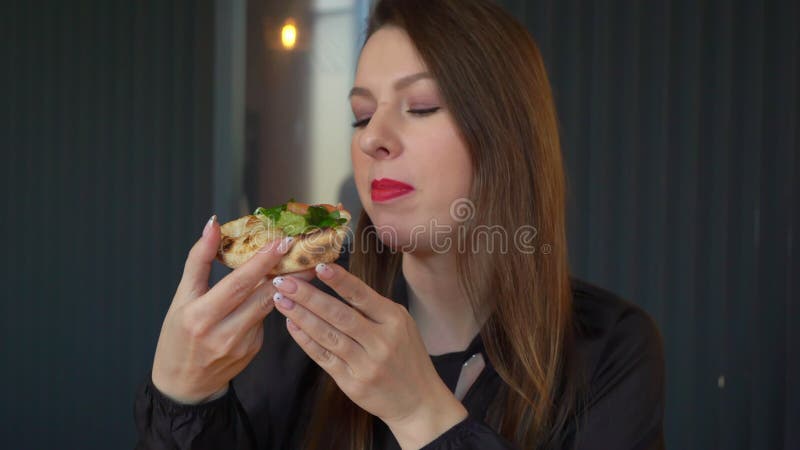 Pizza con salmone rosso formaggio e verde. donna che mangia una fetta di cibo.