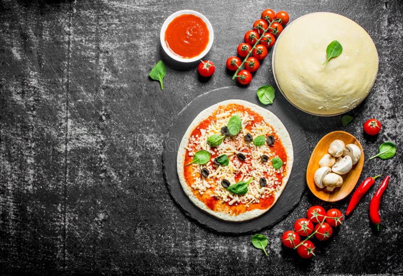 Pizza cruda Pasta con passata di pomodoro, i funghi, le olive ed il peperoncino fotografia stock libera da diritti