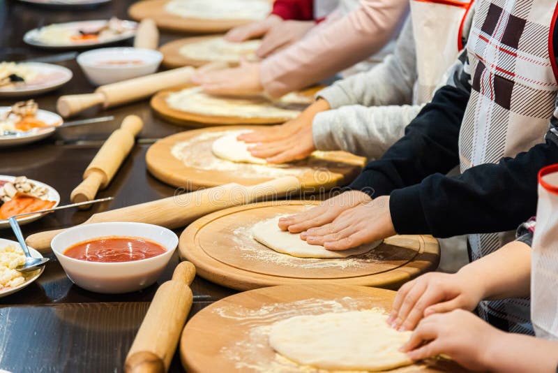 Pizza de cocción infantil. clase magistral del chef en un restaurante clausurado de niños se deshace de la masa fotografía de archivo