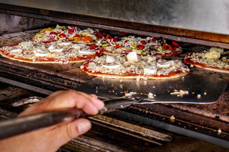 Chef, Der Pizza Kocht Und Sie In Den Ofen Einsetzt, Um Zu Backen