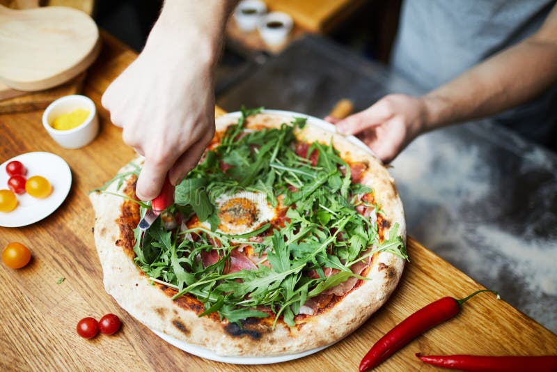Pizza di taglio prima di servire immagine stock libera da diritti Pizza di taglio prima di servire immagine stock libera da diritti