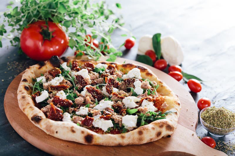 Pizza with dried tomatoes, mozzarella, sausage and rocket