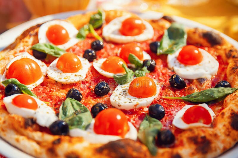 Pizza italiana com tomates, mozzarella, manjericão, azeitonas pretas a bordo restaurante do conceito foto de stock Pizza italiana com tomates, mozzarella, manjericão, azeitonas pretas a bordo restaurante do conceito foto de stock