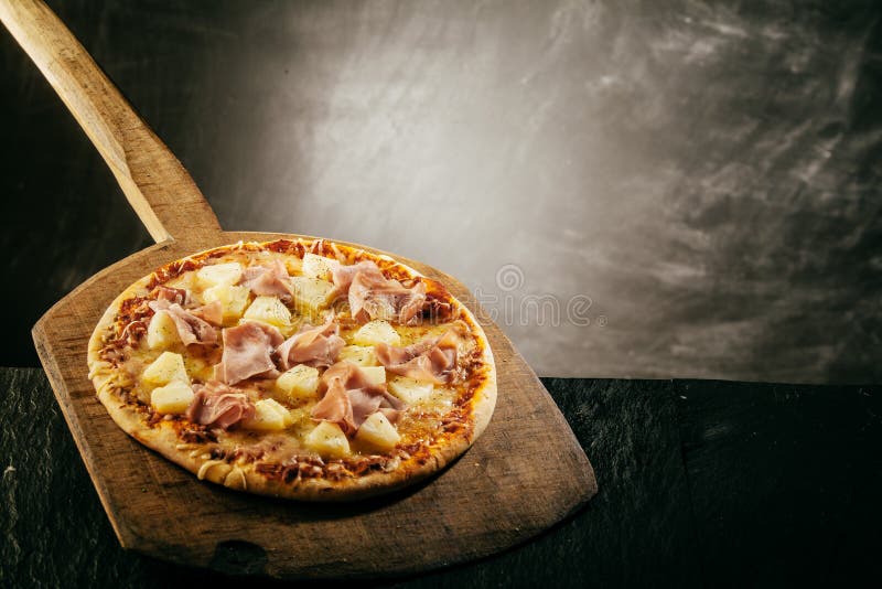 Pizza italiana saporita gastronomica su una buccia di legno fotografia stock Pizza italiana saporita gastronomica su una buccia di legno fotografia stock