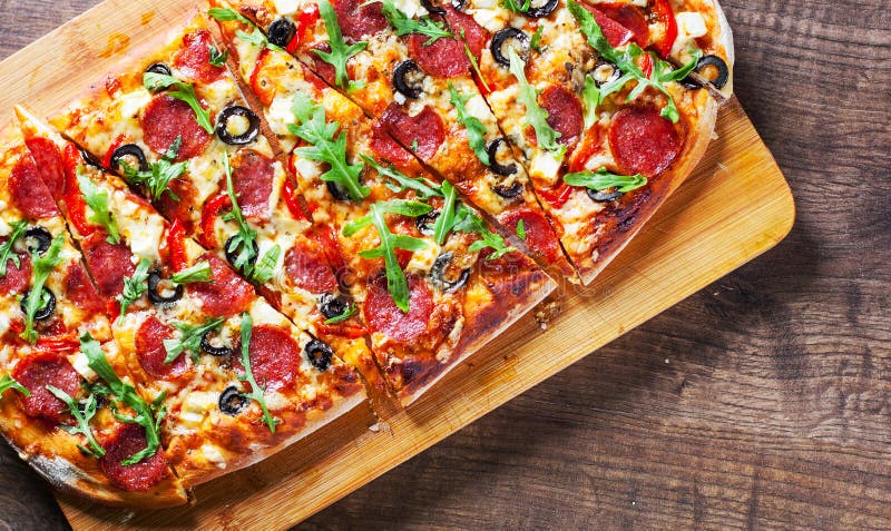 Pizza with Mozzarella cheese, salami, pepper, pepperoni, olives, Spices and Fresh arugula. Italian pizza on wooden table stock image Pizza with Mozzarella cheese, salami, pepper, pepperoni, olives, Spices and Fresh arugula. Italian pizza on wooden table stock image