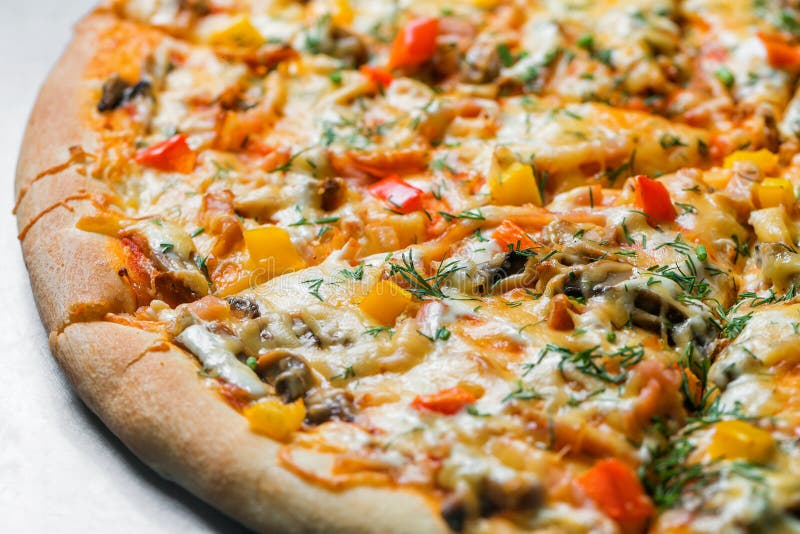 Pizza with mushrooms and vegetables, by cut to pieces on a metal table. selective focus on the filling close-up.