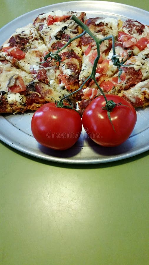 Pizza och vinranka mognade tomater arkivbild Pizza och vinranka mognade tomater arkivbild