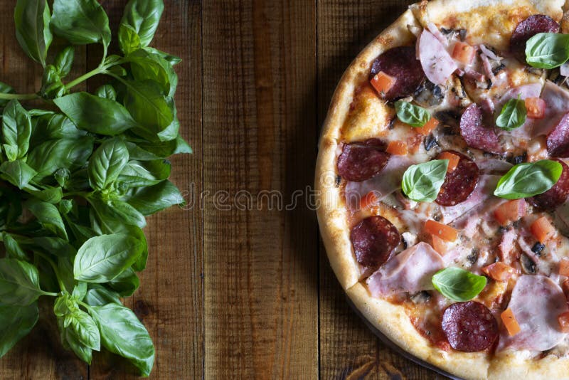 Pizza parfumée délicieuse avec les champignons, le salami, le jambon, les tomates, le mozzarella et le Basil frais sur une table photos libres de droits Pizza parfumée délicieuse avec les champignons, le salami, le jambon, les tomates, le mozzarella et le Basil frais sur une table photos libres de droits
