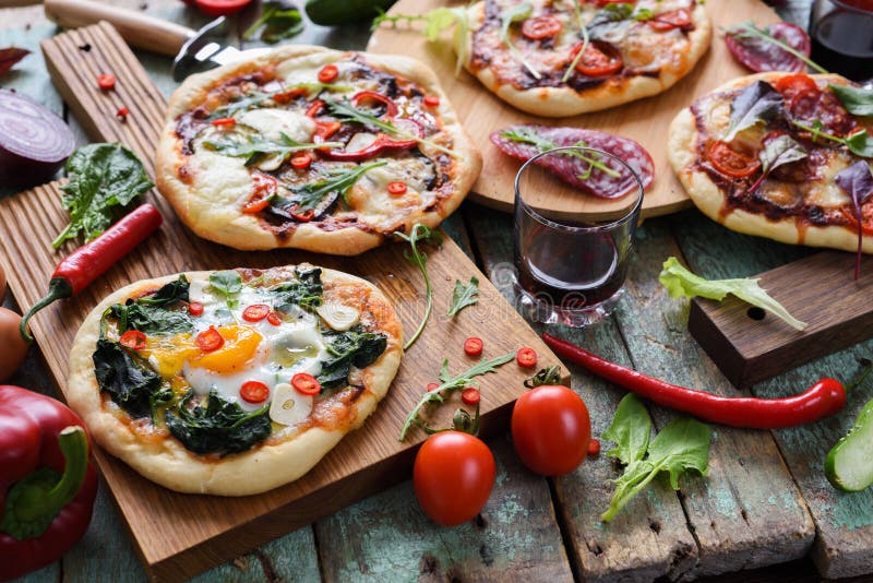 Pizza party. Small homemade rustic pizzas with eggs, spinach, sa royalty free stock images Pizza party. Small homemade rustic pizzas with eggs, spinach, sa royalty free stock images