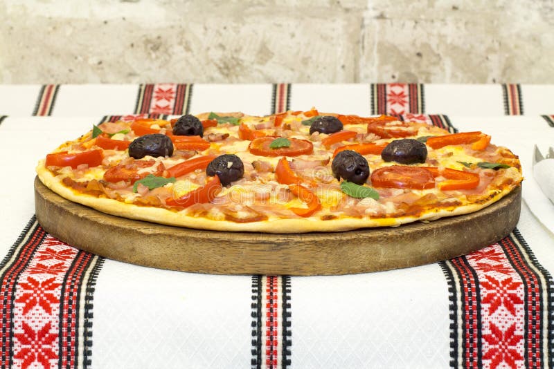 Pizza saboroso com vegetais, manjericão, azeitonas, tomates, pimenta verde na placa de corte, colorido tradicional de pano de tab imagens de stock Pizza saboroso com vegetais, manjericão, azeitonas, tomates, pimenta verde na placa de corte, colorido tradicional de pano de tab imagens de stock