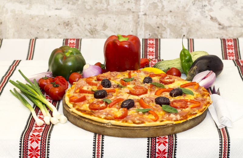 Pizza saboroso com vegetais, manjericão, azeitonas, tomates, pimenta verde na placa de corte, colorido tradicional de pano de tab fotografia de stock Pizza saboroso com vegetais, manjericão, azeitonas, tomates, pimenta verde na placa de corte, colorido tradicional de pano de tab fotografia de stock