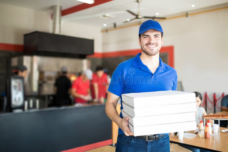Pizzabote, der Pizzakästen im Restaurant hält lizenzfreie stockfotos Pizzabote, der Pizzakästen im Restaurant hält lizenzfreie stockfotos
