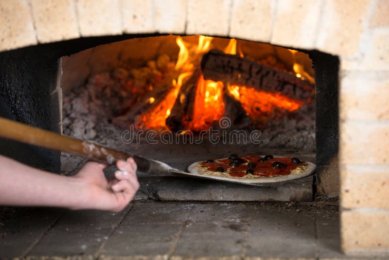 Close-up. Pizza Chef puts the pizza inside the wood oven to bake. Close-up. Pizza Chef puts the pizza inside the wood oven to bake.