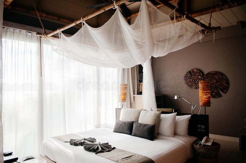 Pi?ce tropicale tha?landaise asiatique de lieu de vill?giature luxueux avec le lit en bois et le rideau blanc photographie stock Pi?ce tropicale tha?landaise asiatique de lieu de vill?giature luxueux avec le lit en bois et le rideau blanc photographie stock