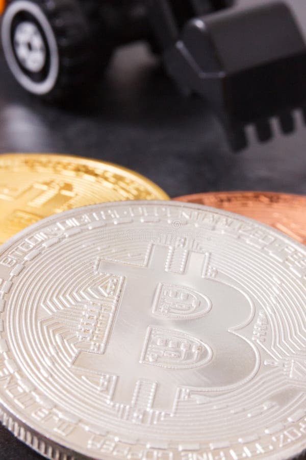 Pièces de monnaie argentées de bitcoin avec l'excavatrice miniature, concept de cryptocurrency de extraction image libre de droits