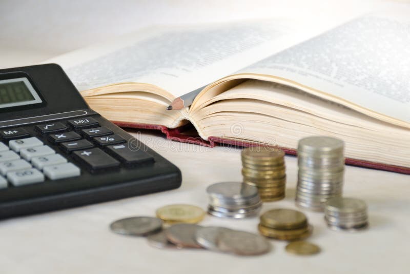 Pièces de monnaie brouillées dans les piles et calculatrice sur le fond d'un livre ouvert Concept de coût de l'éducation élevé photos libres de droits Pièces de monnaie brouillées dans les piles et calculatrice sur le fond d'un livre ouvert Concept de coût de l'éducation élevé photos libres de droits