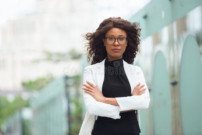 Hands crossed. African-american businesswoman in office attire smiling, looks confident and serious, busy. Finance, business, equality and human rights concept. Beautiful young model, successful. Hands crossed. African-american businesswoman in office attire smiling, looks confident and serious, busy. Finance, business, equality and human rights concept. Beautiful young model, successful.