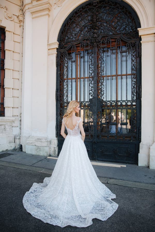 Piękna blondynka włosy panna młoda blisko pacale Kobiety w eleganckiej białej ślubnej sukni obraz stock Piękna blondynka włosy panna młoda blisko pacale Kobiety w eleganckiej białej ślubnej sukni obraz stock
