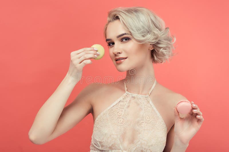 Piękna blondynki kobieta z dwa wyśmienicie macarons zdjęcia royalty free