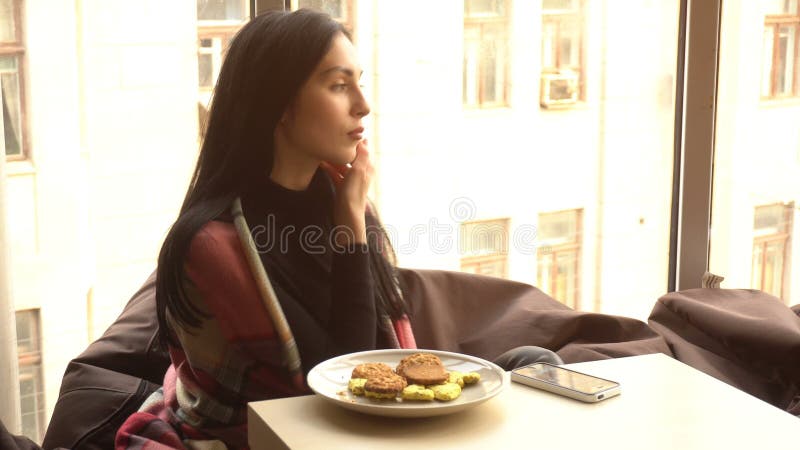 Piękna brunetka siedzi przy stołem
