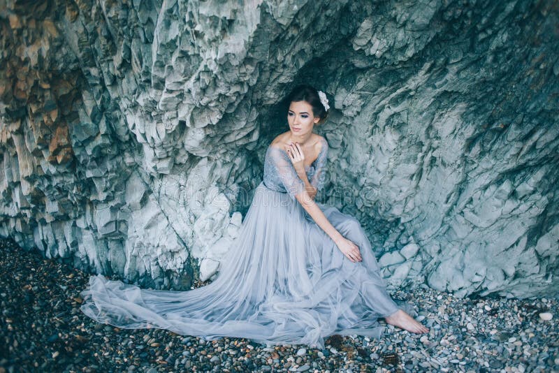 Piękna brunetki kobieta w długiej ślubnej sukni na plaży fotografia stock Piękna brunetki kobieta w długiej ślubnej sukni na plaży fotografia stock