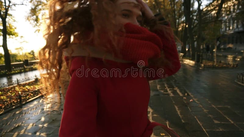 Piękna czerwieni głowy młoda kobieta joyfully biega w kolorowym jesień parku aleją, cieszy się jesieni ulistnienie, zwroty