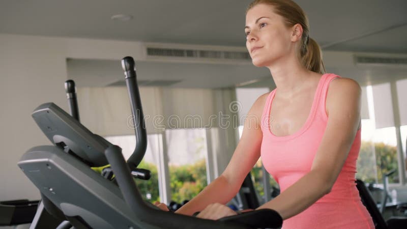 Piękna dysponowana aktywna sportive młoda kobieta pracująca w gym robi ćwiczeniom na velosimulator out