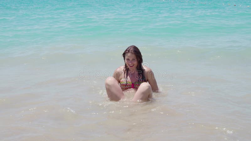 Piękna dziewczyna w kostium kąpielowy zabawy chełbotaniu w seawater z ona ręki up 4K