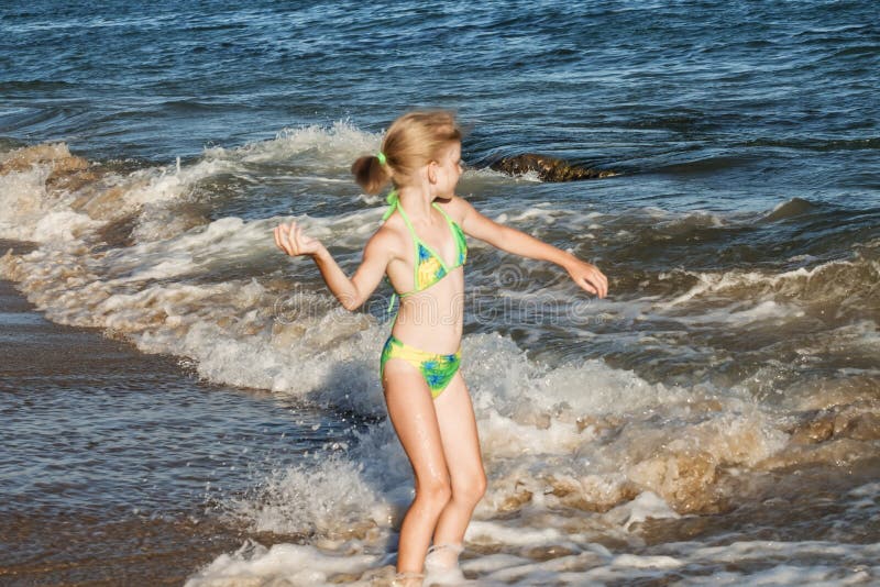 Pi?kna i szcz??liwa dziewczyna w zielonym swimsuit rzuca otoczaka w morzu, pla?owy poj?cie fotografia royalty free Pi?kna i szcz??liwa dziewczyna w zielonym swimsuit rzuca otoczaka w morzu, pla?owy poj?cie fotografia royalty free