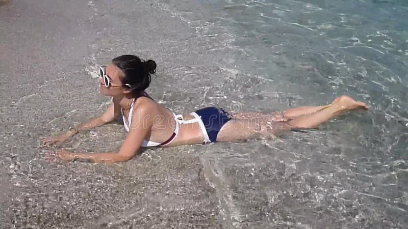 Piękna kobieta opalająca się fale morskie. atrakcyjna dziewczyna w okularach słonecznych na plaży zimny w wodzie zbiory wideo