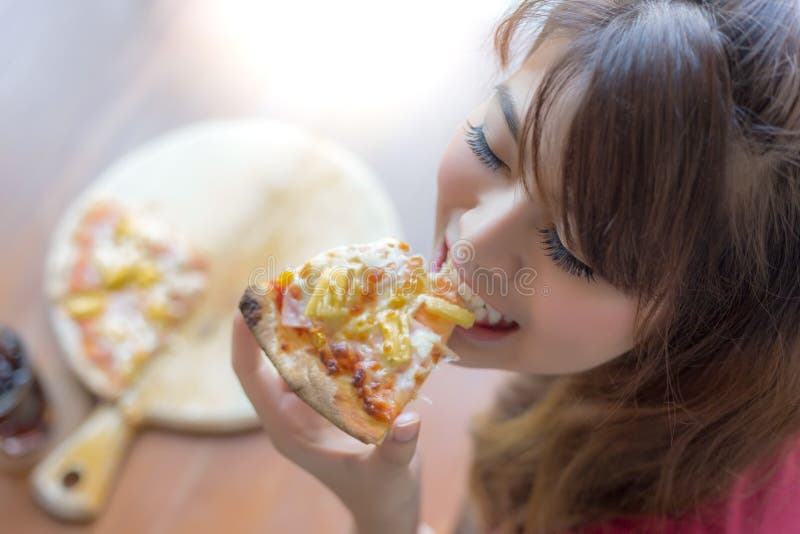 Piękna kobieta trzyma kawałek pizza i je je Ładna azjatykcia dziewczyna czuje szczęśliwego i cieszy się jedzący pizzę Ja patrzeje obraz royalty free Piękna kobieta trzyma kawałek pizza i je je Ładna azjatykcia dziewczyna czuje szczęśliwego i cieszy się jedzący pizzę Ja patrzeje obraz royalty free