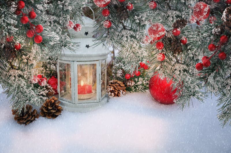 Piękna latarnia świąteczna ze świecą i firowymi gałęziami z szyszkami i czerwonymi jagodami w śniegu Atmosferyczna scena zimowa z
