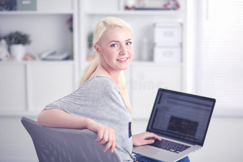 Piękna młoda blond kobieta siedzi na kanapie lub kozetce w domu używać jej laptop zdjęcia royalty free Piękna młoda blond kobieta siedzi na kanapie lub kozetce w domu używać jej laptop zdjęcia royalty free