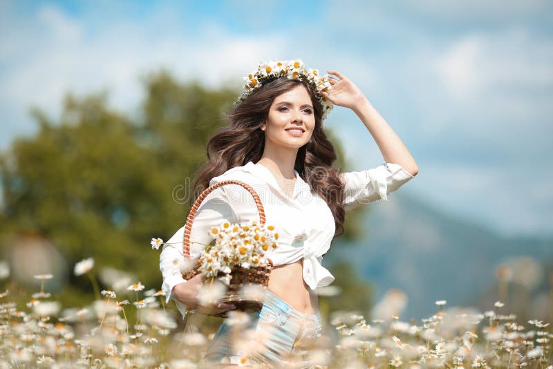 Piękna młoda dziewczyna ono uśmiecha się z koszem kwiaty nad chamomile polem Beztroska szczęśliwa brunetki kobieta z zdrowym fali