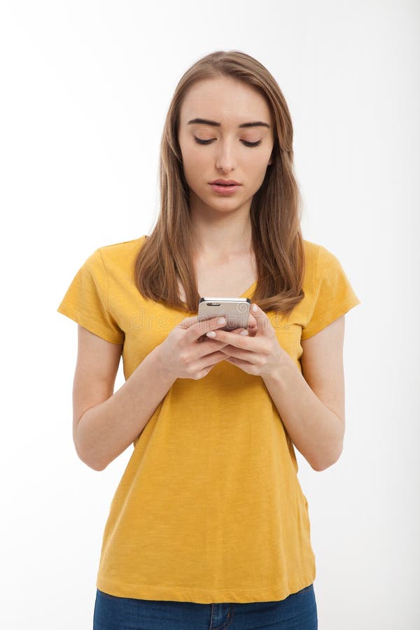 Piękna młoda kobieta jest ubranym żółtą t koszula i texting na smartphone odizolowywającym na bielu Odbitkowa przestrzeń up i egz zdjęcie stock Piękna młoda kobieta jest ubranym żółtą t koszula i texting na smartphone odizolowywającym na bielu Odbitkowa przestrzeń up i egz zdjęcie stock
