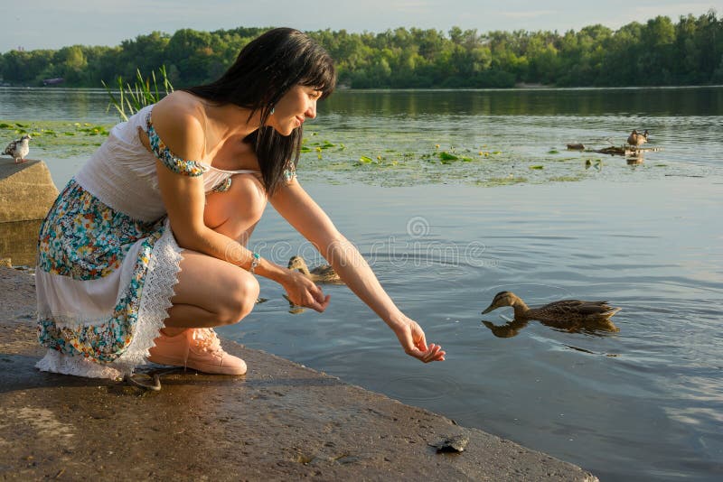 Piękna młoda kobieta karmi ptaki na jeziorze Piękny yo