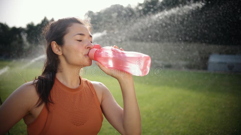 Piękna młoda kobieta sportowa pije wodę z plastikowych butelek