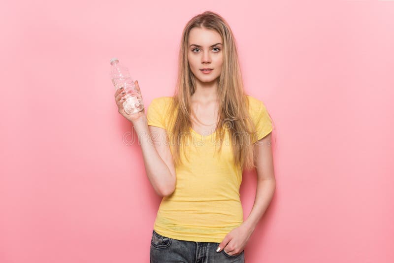 Piękna młoda kobieta z perfect ciała mienia bidonu plastikową pozycją blisko ściany zdjęcia royalty free Piękna młoda kobieta z perfect ciała mienia bidonu plastikową pozycją blisko ściany zdjęcia royalty free