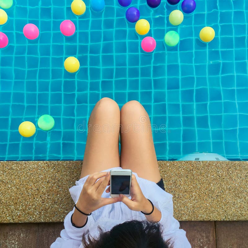 Piękna młoda kobieta z pięknego uśmiechu czytelniczym dobre'em wieści na telefonu komórkowego obsiadaniu poolside obrazy stock Piękna młoda kobieta z pięknego uśmiechu czytelniczym dobre'em wieści na telefonu komórkowego obsiadaniu poolside obrazy stock