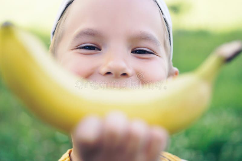 Piękna młoda uśmiechnięta Kaukaska chłopiec w nakrętce z bananowym uśmiechem na natury tle zdjęcie royalty free Piękna młoda uśmiechnięta Kaukaska chłopiec w nakrętce z bananowym uśmiechem na natury tle zdjęcie royalty free