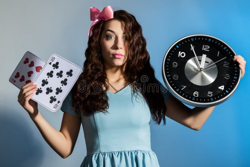 Beautiful pinup girl in a blue dress holding big clock on a blue background. Beautiful pinup girl in a blue dress holding big clock on a blue background.