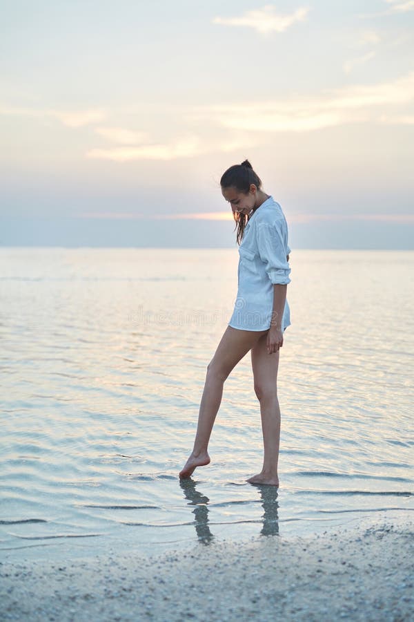 Piękna plciowa kobieta w białym koszula, bikini odprowadzeniu na plaży przeciw i fotografia stock Piękna plciowa kobieta w białym koszula, bikini odprowadzeniu na plaży przeciw i fotografia stock